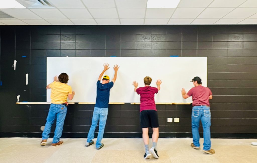 Left to right: Ben Hyde, Reed Alexander, Kaleb Eiler, and Nicholas Schivers from Civil Construction CTE help hang the whiteboard.